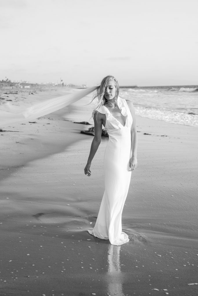 beach wedding bride hops in ocean and gets wet with dress and veil