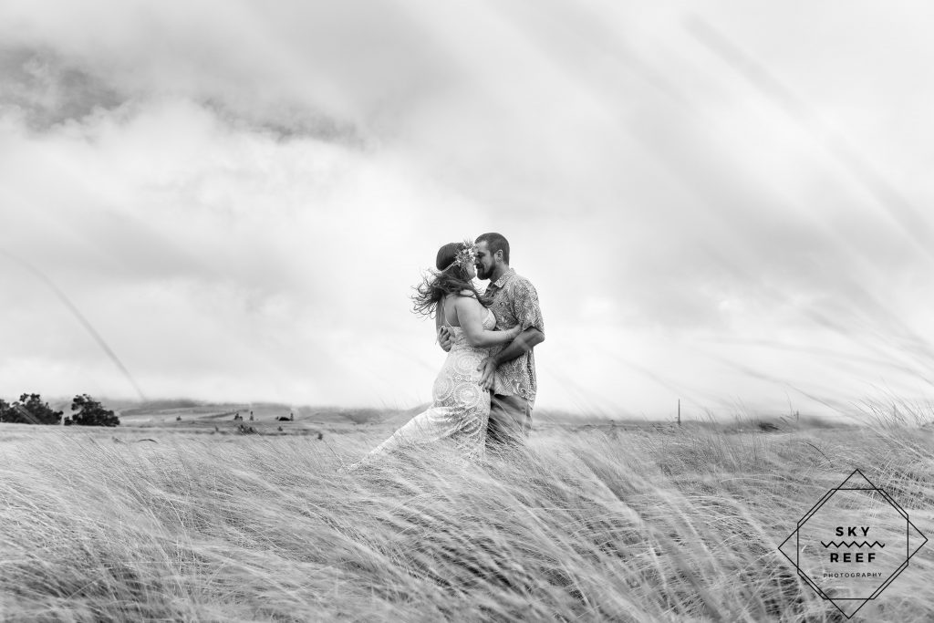 black and white photo of couple kissing in field in Waimea Hawaii